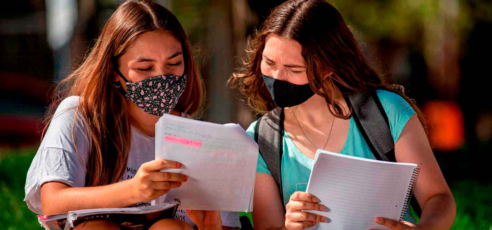 Dos chicas estudian juntas leyendo apuntes