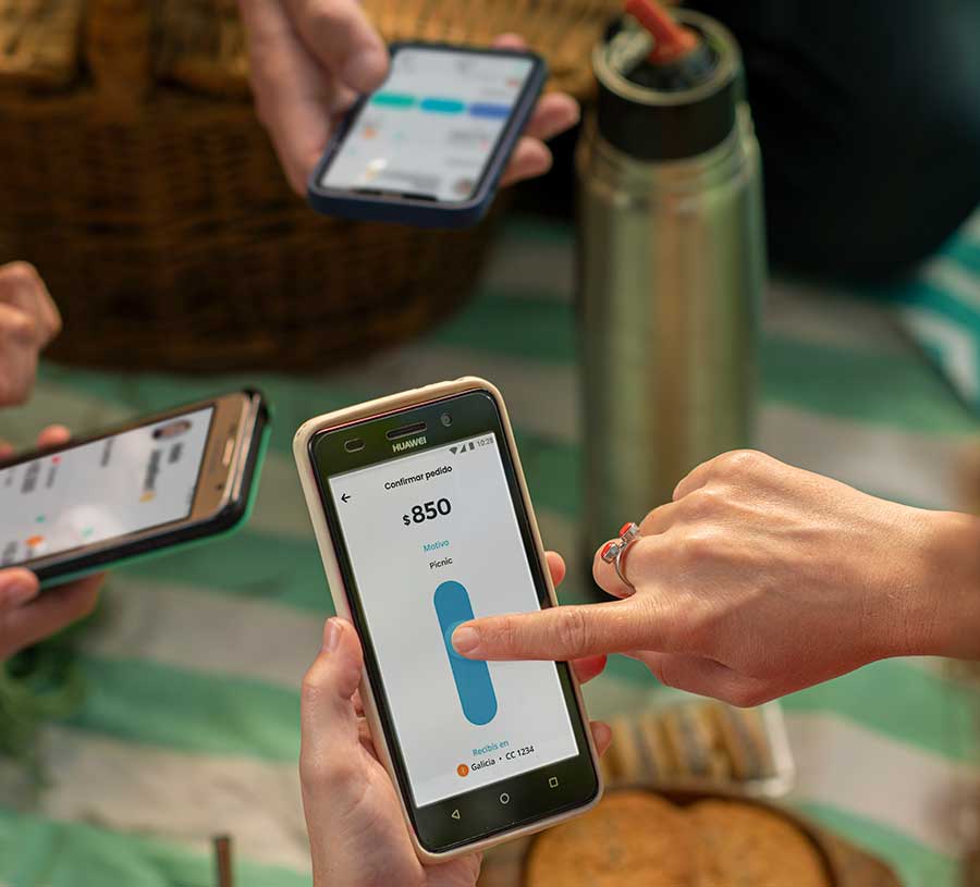 manos de distintas personas usando sus celulares en una reunión transfiriendo dinero