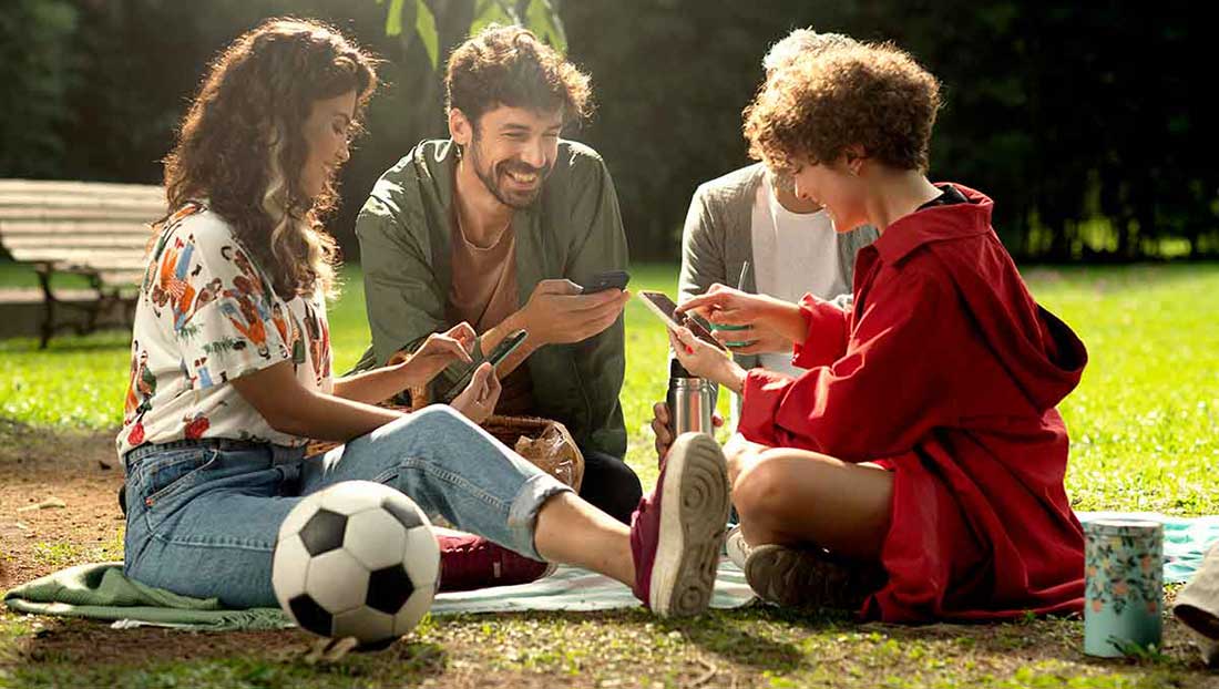 amigos de picnic usando sus celulares para transferir dinero
