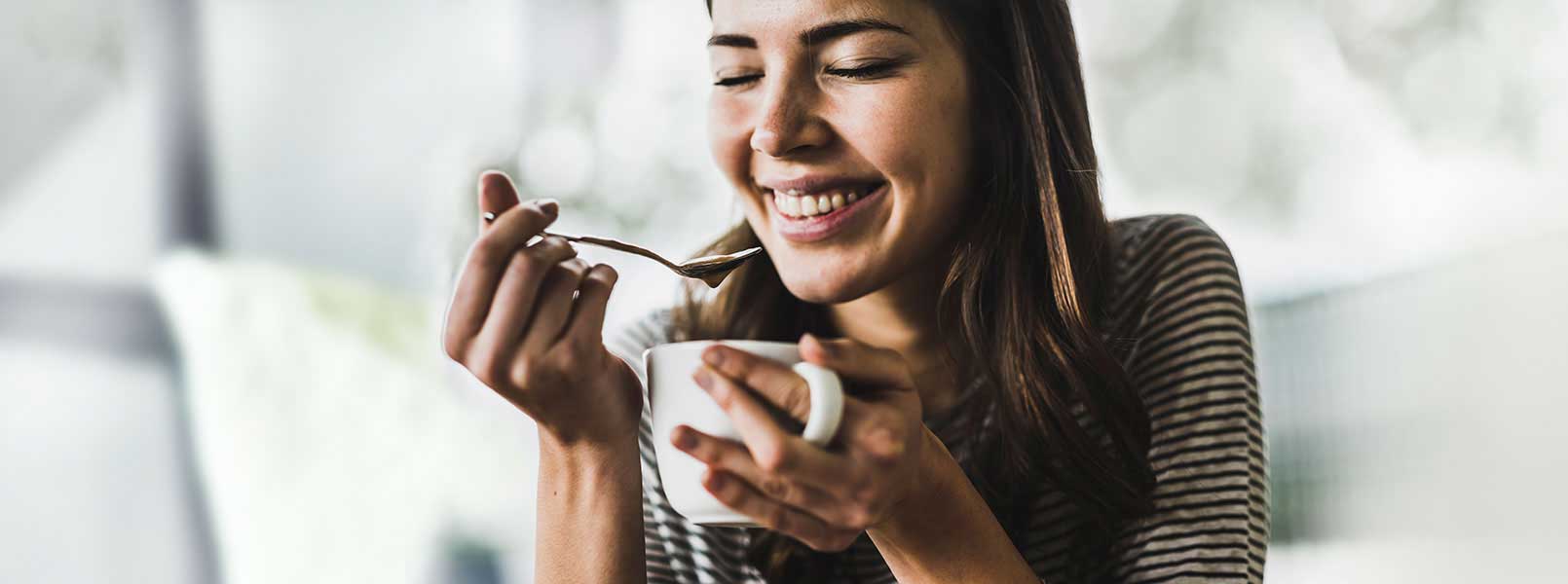 Una mujer riéndose mientras toma café